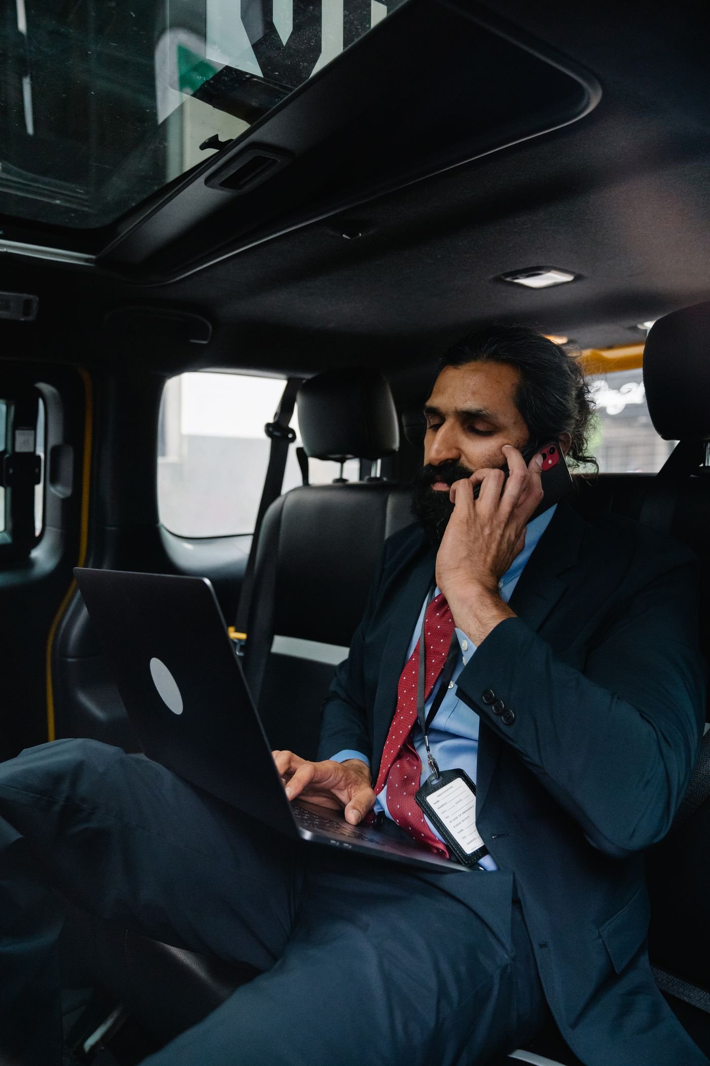 A man working on a laptop in the back seat of his car